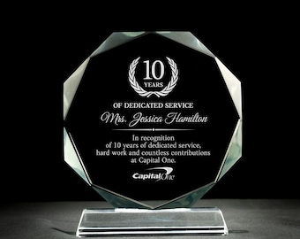 May include: A clear glass octagonal award plaque with a black background and white text. The plaque features a laurel wreath with the number 10 in the center and the text "Years" below. The text "Of Dedicated Service" is below the wreath, followed by the name "Mrs. Jessica Hamilton". The text "In recognition of 10 years of dedicated service, hard work and countless contributions at Capital One." is below the name. The Capital One logo is at the bottom of the plaque.