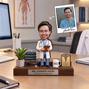 May include: A custom bobblehead figurine of a doctor wearing a white coat and blue scrubs, holding a clipboard. The base features a nameplate reading DR. ANDREW DAVIS DOCTOR OF MEDICINE, a miniature stethoscope, a mug labeled MD, and a plaque.