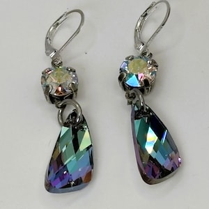 May include: A pair of silver-toned drop earrings. Each earring features a round, iridescent crystal at the top, connected to a teardrop-shaped, multi-colored crystal pendant. The pendants reflect shades of blue, green, and purple.