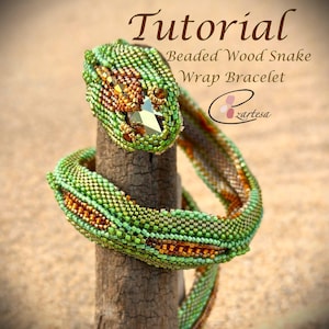 May include: A green and gold beaded snake wrap bracelet with a crystal accent. The bracelet is wrapped around a wooden stick. The text "Tutorial Beaded Wood Snake Wrap Bracelet" is above the bracelet. The text "zartesa" is below the bracelet.