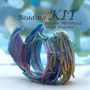 May include: A beaded mermaid wrap bracelet kit. The bracelet is made of small, colorful beads in shades of blue, purple, and gold. The text "Beading KIT" and "Beaded Mermaid Wrap Bracelet" are displayed on the image.
