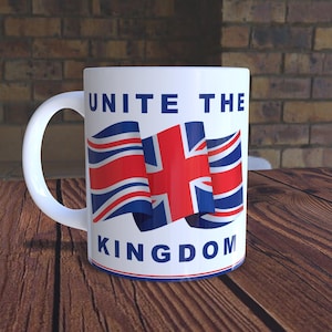 May include: White ceramic mug with a large handle, featuring the text "UNITE THE KINGDOM" in blue. The mug displays a stylized Union Jack flag in red, white, and blue. The mug sits on a wooden surface.