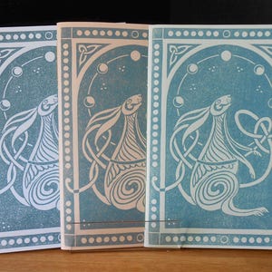 May include: Three blue and white cards with a decorative border and a stylized illustration of a hare with a Celtic knot design. The hare is surrounded by a circle of moons.