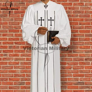 May include: White clergy robe with black crosses and vertical stripes. The robe has long sleeves and is held by a person. The text "Victorian Military" is visible. The background is a brick wall.