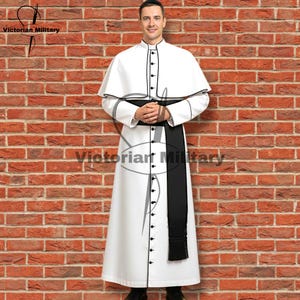 May include: A white robe with black trim and buttons, featuring a matching cape and a black sash. The robe is worn by a person standing in front of a brick wall. The text "Victorian Military" is visible.