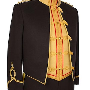 Puede incluir: Chaqueta negra de estilo militar con ribetes y detalles dorados. La chaqueta presenta un cuello alto, botones dorados y bordados dorados decorativos en las mangas. El interior es de color beige claro con detalles rojos y dorados.