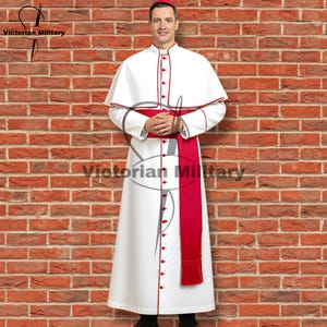 May include: A white robe with red trim and buttons, a red sash, and a matching cape. The outfit is worn by a person standing in front of a brick wall. The text "Victorian Military" is visible in the image.
