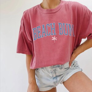 a woman wearing a red beach bum t - shirt
