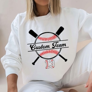 May include: White sweatshirt with a baseball graphic and the text "Custom Team" with the number 13.