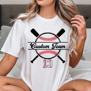 May include: White t-shirt with a baseball graphic and the text "Custom Team" and the number "13".