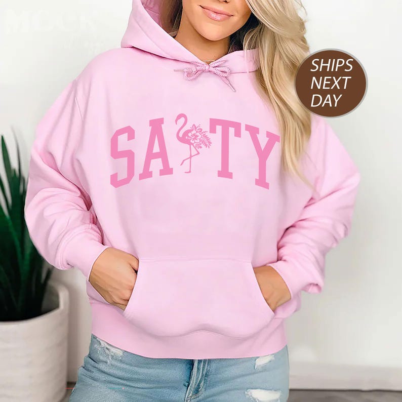a woman wearing a pink hoodie with a pink flamingo on it