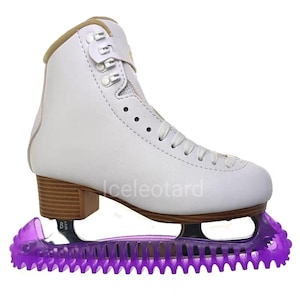May include: White figure skate with a brown heel and a purple blade guard. The skate has laces and a buckle closure. The text "Iceleotard" is visible on the side of the skate. The skate size is 8 1/2.