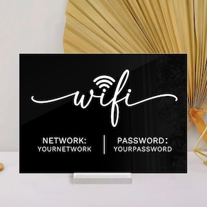 Könnte beinhalten: Schwarzes Acryl-WLAN-Schild mit weißer Schrift "wifi". Darunter stehen die Worte "NETWORK: YOURNETWORK" und "PASSWORD: YOURPASSWORD". Das Schild steht auf einer weißen Oberfläche.