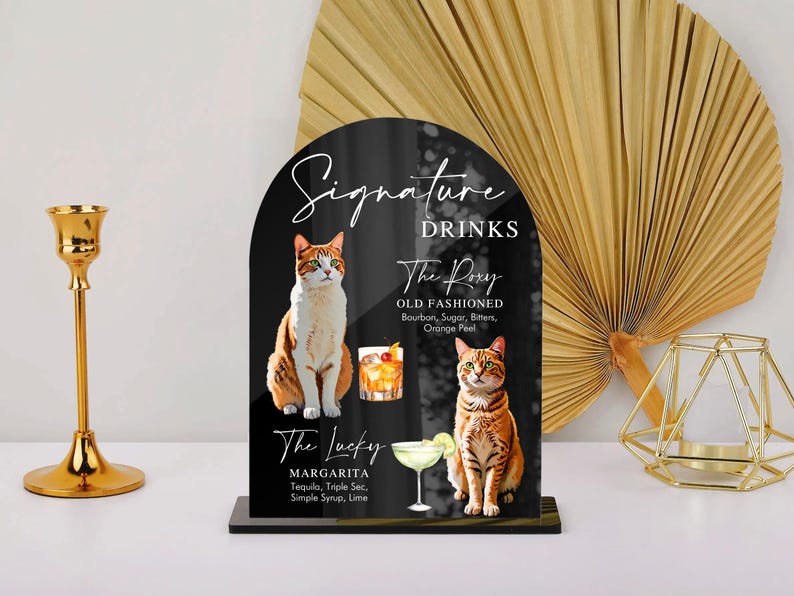 May include: Black and white sign with the text "Signature Drinks" and two cat illustrations. The sign lists two drinks: "The Pory Old Fashioned" and "The Lucky Margarita".