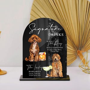 May include: Black sign with white text listing "Signature Drinks" and two drink options: "The Rory Old Fashioned" and "The Lucky Margarita".  Each drink is illustrated with a cocktail and a dog.