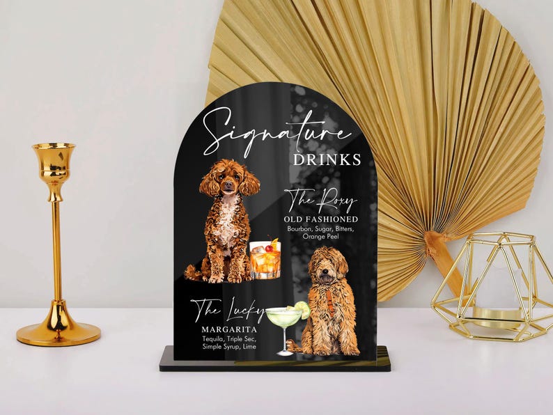 May include: Black sign with white text listing "Signature Drinks" and two drink options: "The Rory Old Fashioned" and "The Lucky Margarita".  Each drink is illustrated with a cocktail and a dog.