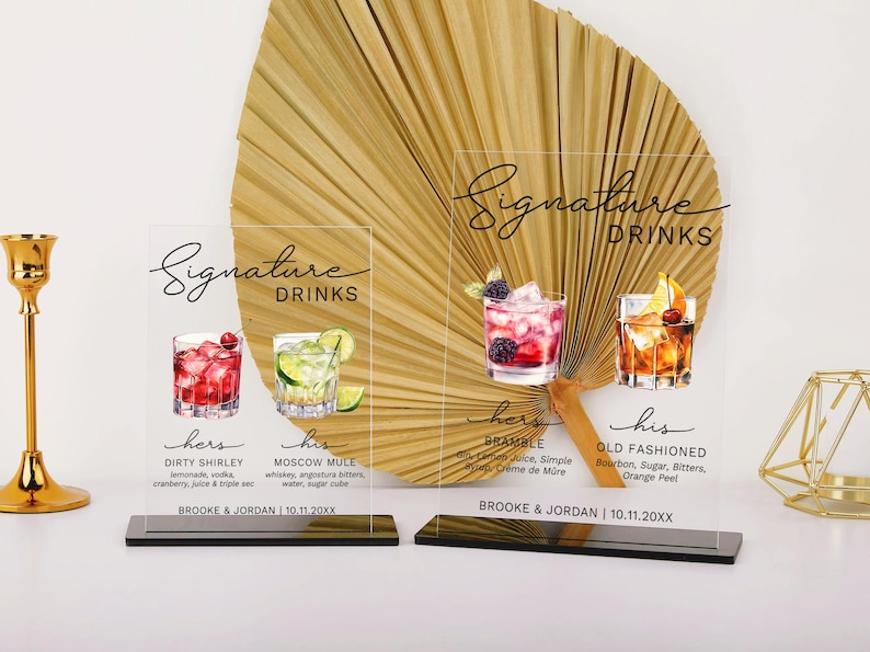 May include: Two acrylic signs with black text and illustrations of cocktails. The signs are labeled "Signature Drinks" and list the drinks "Dirty Shirley", "Moscow Mule", "Bramble", and "Old Fashioned".