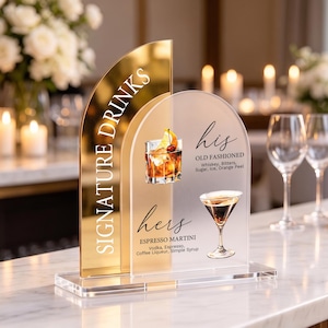 May include: A dual-layered arched acrylic sign featuring a gold-toned back panel and a frosted front panel. The text reads SIGNATURE DRINKS, his OLD FASHIONED with ingredients, and hers ESPRESSO MARTINI with ingredients, accompanied by cocktail illustrations.