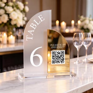 May include: A semi-circular table number sign featuring a frosted acrylic panel with the white text TABLE 6 and a gold mirrored acrylic panel with a QR code, the text PLEASE SCAN AND ENJOY!, and the names OLIVER & EVELYN with the date 10.05.2026.