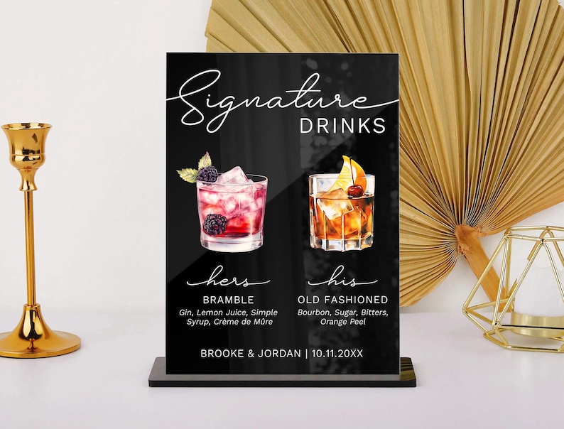 May include: Black sign with white text that reads "Signature Drinks". The sign has two images of cocktails, one with a red drink and the other with a brown drink. The text below the images reads "hers" and "his" with the names of the drinks and ingredients listed below. The bottom of the sign reads "Brooke & Jordan | 10.11.20XX".