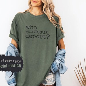 moss green comfort colors shirt on a woman with black typewriter text that reads "who would Jesus deport?" in the middle of the front of the t shirt