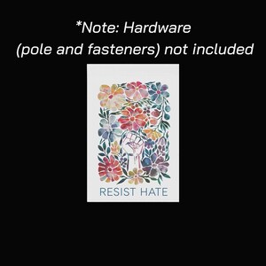 May include: A watercolor print featuring a raised fist with dripping paint, surrounded by colorful flowers. The words "RESIST HATE" are at the bottom. The text "*Note: Hardware (pole and fasteners) not included" is at the top.