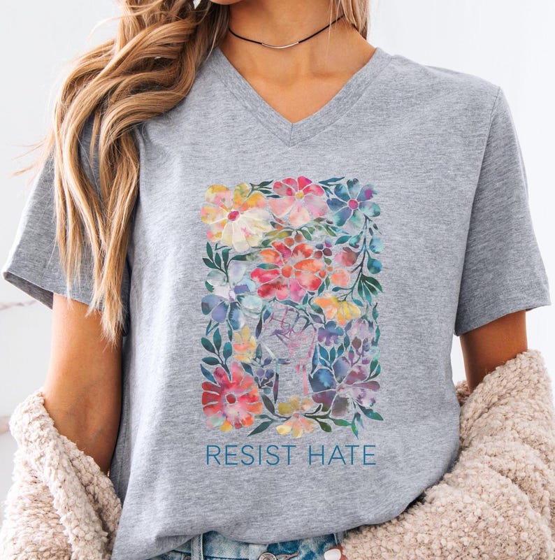 A gray v-neck t-shirt with a floral print and the words 'Resist Hate' in blue text.