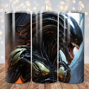 May include: Three stainless steel tumblers with a black and gold alien creature graphic. The alien has a large head with a sharp jaw and teeth. The background is a dark blue and gray.
