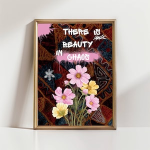 Puede incluir: Impresión artística enmarcada con un arreglo floral de cosmos rosas y amarillos. La obra de arte incluye el texto "THERE IS BEAUTY IN CHAOS" en estilo graffiti blanco y rosa. El fondo tiene un diseño estampado.