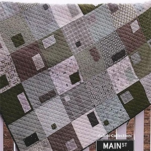 May include: A quilt pattern called "Mixed Bag" from the "Mainst Sweetwater" fabric collection. The quilt is made of various shades of gray, brown, and green fabric squares. The quilt is 64 inches by 64 inches.