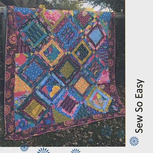 May include: A colorful quilt with a diamond pattern, featuring various fabrics in shades of blue, pink, yellow, and green. The quilt is displayed outdoors, with the text "Past Times" and "Sew So Easy" visible. Designed by Lynne Wilson.