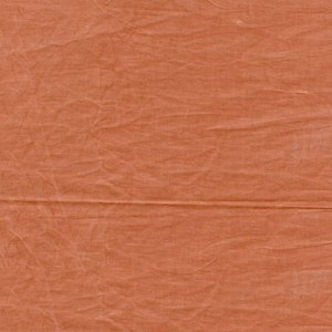 Könnte beinhalten: Nahaufnahme eines strukturierten, orangebraunen Stoffes. Das Material hat ein faltiges Aussehen mit horizontalen und vertikalen Falten. Die Farbe ist ein warmer, erdiger Ton, der auf ein natürliches Textil hindeutet. Die Oberfläche des Stoffes ist leicht uneben.