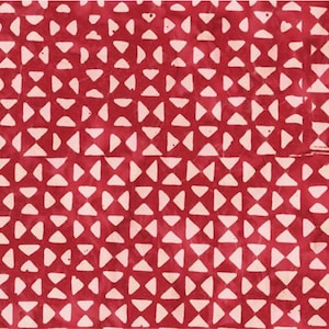Puede incluir: Primer plano de una tela roja con un patrón repetitivo de diseños blancos en forma de lazo. El patrón está espaciado uniformemente, creando un efecto texturizado. La tela tiene un aspecto ligeramente descolorido.