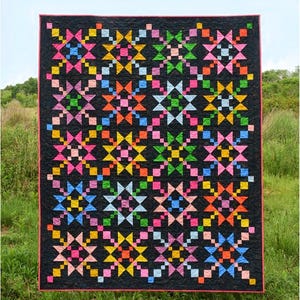 May include: A quilt pattern titled Scenic Waypoint by Meadow Mist Designs. The quilt features a black background with a repeating star block design in vibrant colors including pink, yellow, orange, green, and blue. The text includes A fat quarter friendly pattern in baby, throw, and twin sizes.