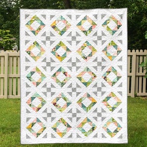 May include: A quilt pattern titled Diamonds and Pearls by Meadow Mist Designs. The quilt features a repeating geometric block design with white, gray, and multi-colored floral fabric squares. The text includes pattern details and size options.