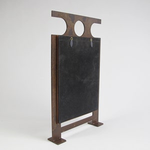 May include: A brown metal sign with a rectangular black surface. The sign has a horizontal top section with two circular cutouts and a rectangular base. The sign is designed to stand upright.