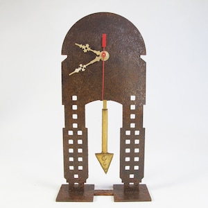 May include: A rusty metal clock with a gold pendulum and hands. The clock is shaped like a building with a pointed roof and windows.
