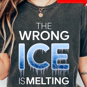 Puede incluir: Camiseta gris oscuro con el texto blanco y azul "THE WRONG ICE IS MELTING". La palabra "ICE" está diseñada para parecer hielo derritiéndose con carámbanos. La camiseta tiene cuello redondo.