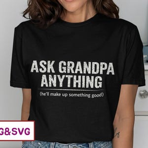 May include: Black t-shirt with the text "ASK GRANDPA ANYTHING" in white, with the phrase "(he'll make up something good)" underneath. The shirt is a casual style.