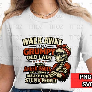 Puede incluir: Camiseta blanca con un gráfico que dice "Walk Away I am a Grumpy Old Lady". El diseño presenta un esqueleto con gafas de sol y una bandana roja. La camiseta también tiene el texto "I have anger issues and a serious dislike for stupid people".