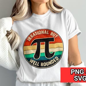 Op de afbeelding: Wit T-shirt met een kleurrijk grafisch ontwerp van het wiskundige symbool Pi, met de tekst "Irrational but Well Rounded" in een cirkelvormig ontwerp. Het ontwerp bevat rode, oranje, gele, groene en blauwe strepen. Een rode rechthoek met "PNG & SVG" staat rechtsonder.