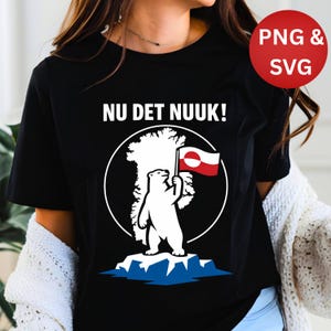 May include: Black t-shirt with a white graphic of a polar bear holding a Greenlandic flag, standing on a blue iceberg, and the text "NU DET NUUK!". A red circle with "PNG & SVG" is in the upper right.