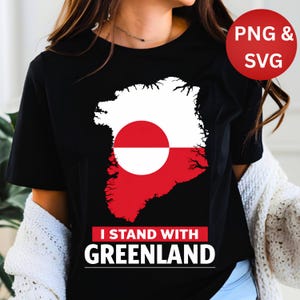 May include: Black t-shirt featuring a graphic of Greenland's map in white and red, with a red circle in the center. The text "I STAND WITH GREENLAND" is displayed below the graphic. A red circle with "PNG & SVG" is in the upper right.
