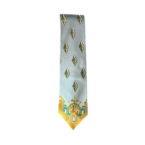 Puede incluir: Una corbata con fondo azul claro y rayas verticales negras. La corbata presenta diseños dorados de flor de lis y diseños dorados y turquesa ornamentados en la parte inferior. Un accesorio clásico.