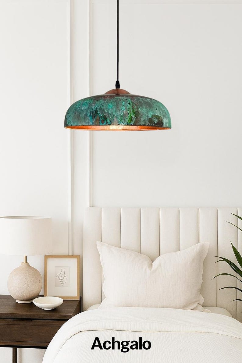 May include: A ceiling pendant light with a domed shade. The shade has a textured, weathered finish in green and copper tones. The light hangs from a black cord. The word "Achgalo" is printed at the bottom of the image.