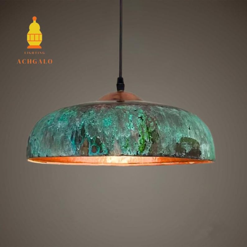 May include: A dome-shaped pendant light with a copper top and a verdigris-effect shade in shades of green and blue. The light hangs from a black cord. The brand name "ACHGALO" is visible. The shade's diameter is approximately 40 cm.