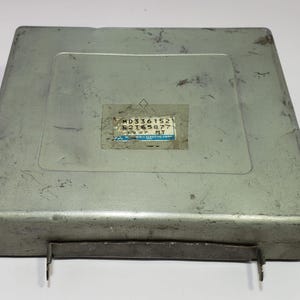 May include: A silver metal box with a label that reads "MD336152 E2T43877 MT".