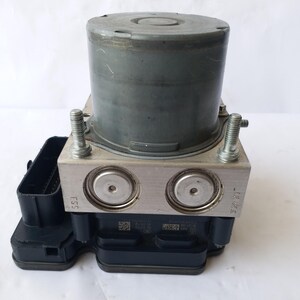 Op de afbeelding: Een auto ABS-module, bestaande uit een cilindrische grijze component op een zilveren metalen basis met twee cirkelvormige openingen. De module bevat een zwarte rechthoekige connector en twee zilveren bouten. Ontworpen voor voertuigremsystemen.