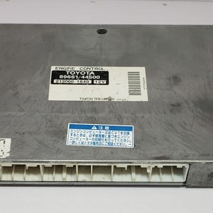 May include: A silver engine control unit with a white label that reads "ENGINE CONTROL TOYOTA 89661-44500 212000-1640 12V FUJITSU TEN LIMO" and a blue label with Japanese text.