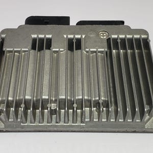 Op de afbeelding: Zilverkleurige elektronische regeleenheid (ECM) met een geribbeld oppervlak en twee zwarte connectoren. De rechthoekige module heeft afgeronde hoeken en wordt waarschijnlijk gebruikt in auto-toepassingen.
